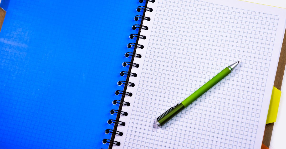 Open graphing notebook with a green pen on a white desk surface.